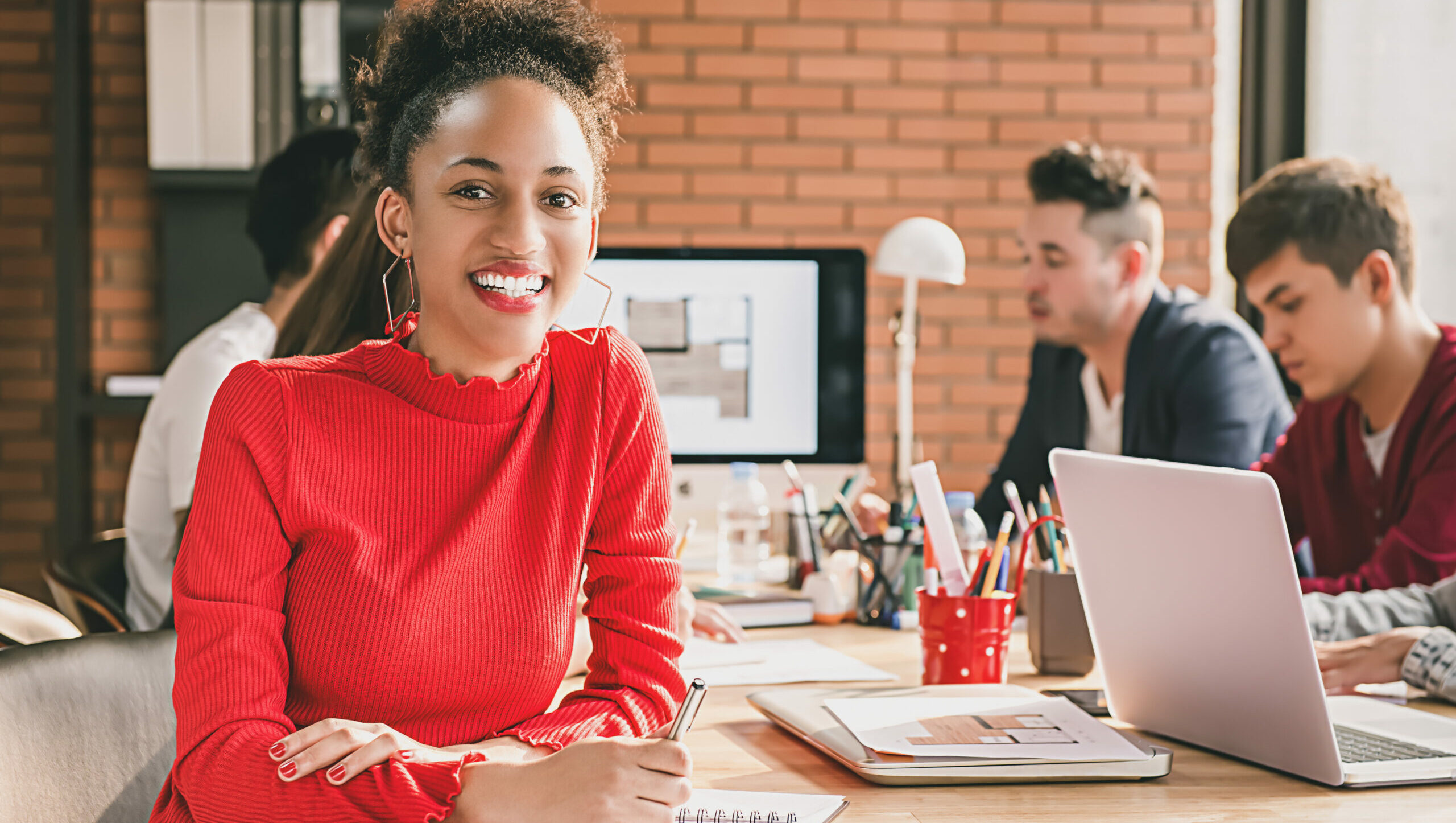 A woman smiles while working in an office with her coworkers.